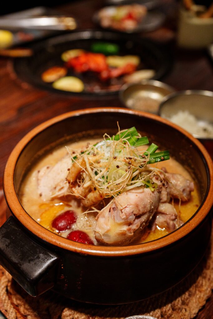 Korean samgyetang, a whole young chicken stuffed with rice and ginseng, simmering in an earthenware pot