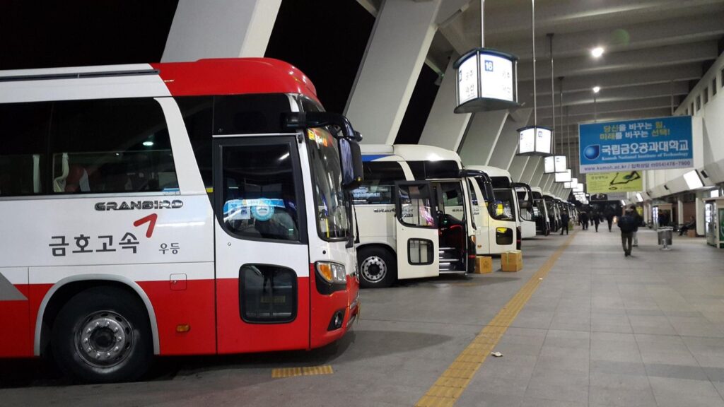 Express and intercity buses lined up at their gates in a Korean bus terminal at night