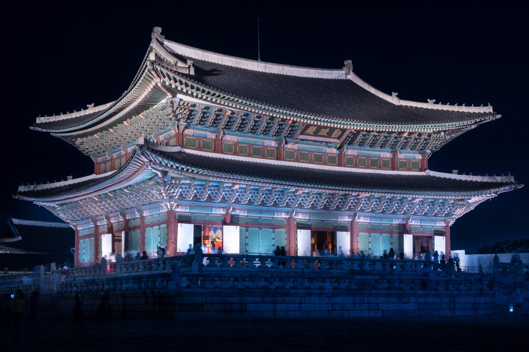 Geunjeongjeon throne hall at Gyeongbokgung at night, its doors open and the interior lit