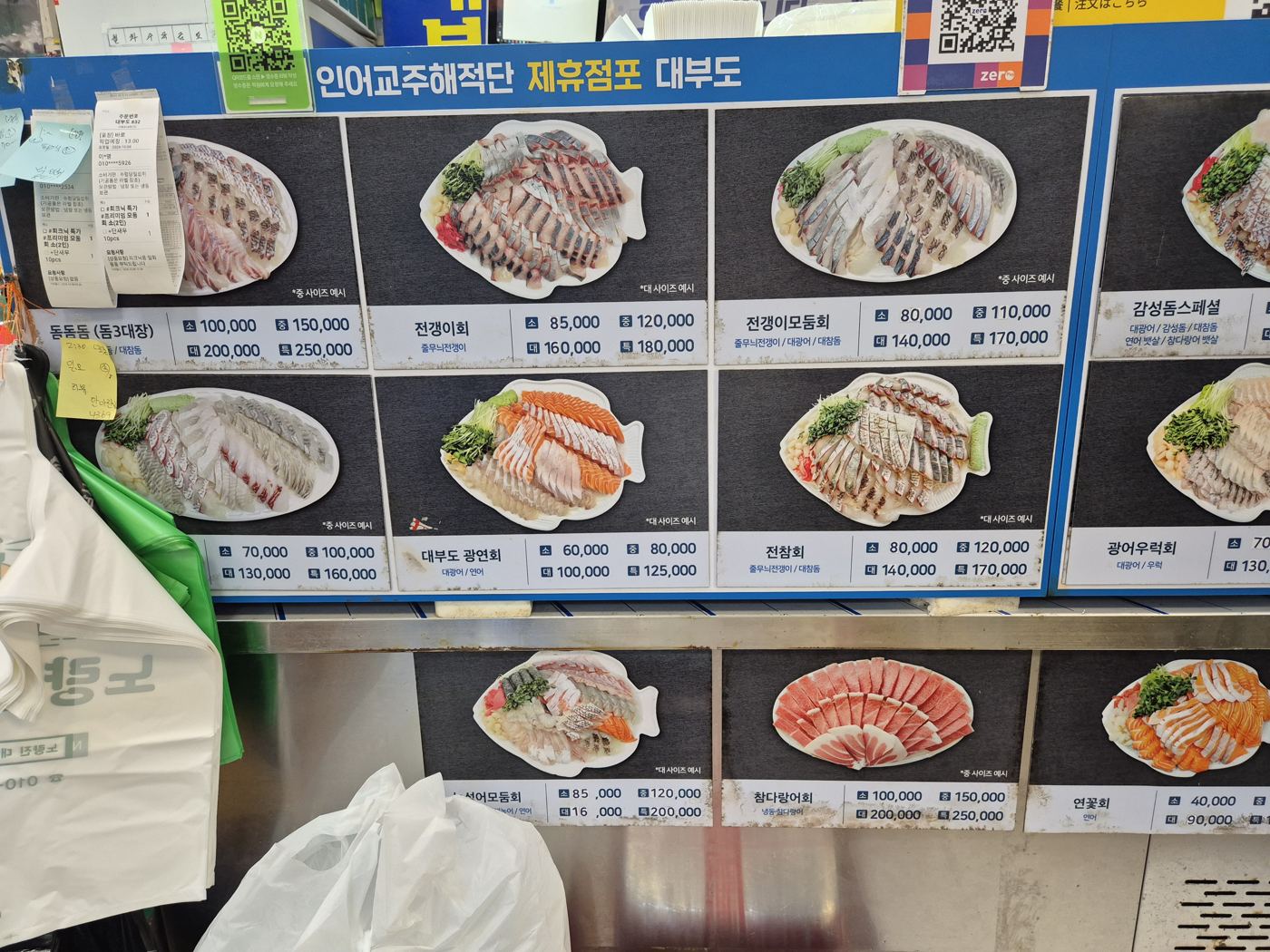 The menu board of a Tpirates partner shop: photos of fish-shaped platters — barred knifejaw, jack sashimi, mixed jack platter, flounder — with prices.
